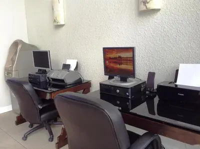 a room with a desk with a computer and chairs at Ramada by Wyndham Oceanside in Oceanside