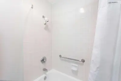 a bathroom with a shower with a white tub at Ramada by Wyndham Oceanside in Oceanside