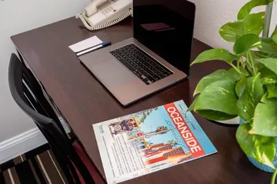 a table with a laptop computer and a magazine at The Hotel Oceanside in Oceanside