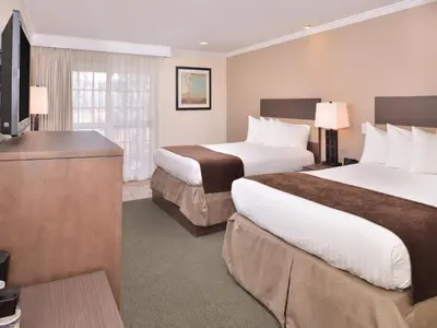a hotel room with two beds and a flat screen tv at Best Western Capistrano Inn in San Juan Capistrano