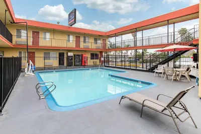 a pool at a hotel with two chairs and a table at Howard Johnson Suites by Wyndham San Diego Chula Vista BayFront in Chula Vista