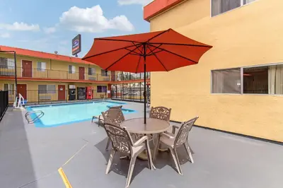 a table and chairs with an umbrella next to a pool at Howard Johnson Suites by Wyndham San Diego Chula Vista BayFront in Chula Vista