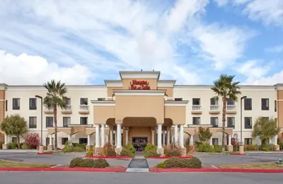 a large building with palm trees in front of it at Hampton Inn & Suites by Hilton Hemet Menifee Murrieta in Hemet