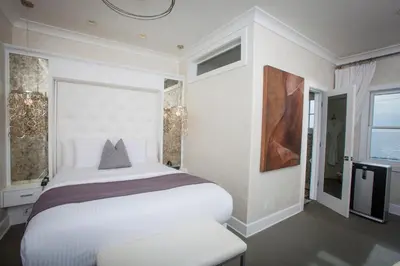 a white bedroom with a large bed and a window at La Casa Del Camino in Laguna Beach
