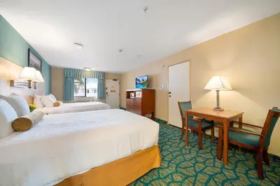 a hotel room with two beds and a desk at Casablanca Inn in San Clemente
