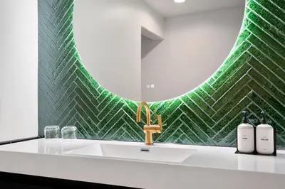 a bathroom with a sink with a green tile wall at Casablanca Inn in San Clemente