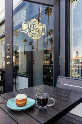 a table with a cup of coffee and a pastry at The Fin Hotel, Tapestry Collection by Hilton in Oceanside