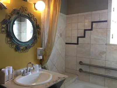 a bathroom with a sink and a mirror and a tub at Les Artistes Inn in San Diego