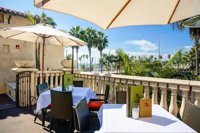 a patio with tables and umbrellas on a balcony at Balboa Inn, On The Beach At Newport in Newport Beach