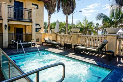 a swimming pool with chairs and a building at Balboa Inn, On The Beach At Newport in Newport Beach