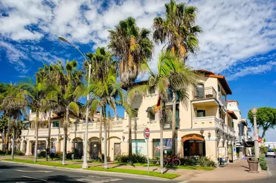 a building with palm trees in front of a street at Balboa Inn, On The Beach At Newport in Newport Beach