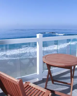 a table and a chair on a balcony with the ocean at Capri Laguna on the Beach - A Boutique Hotel in Laguna Beach