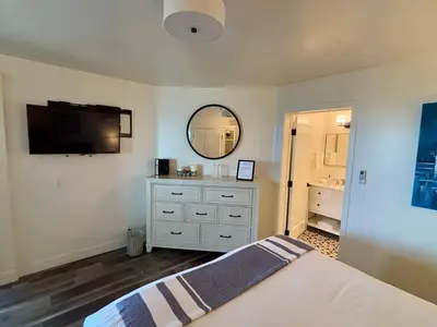 a bedroom with a bed and a mirror and a dresser at Casa Tropicana in San Clemente
