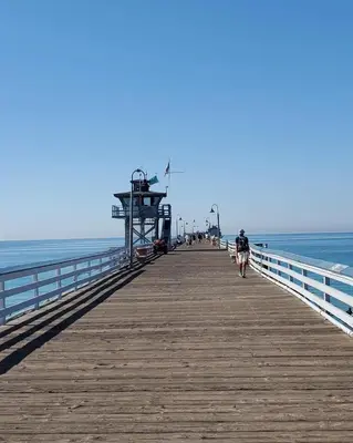 a person walking on a pier next to the ocean at Casa Tropicana in San Clemente