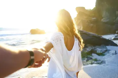 a couple holding hands while walking on the beach at La Jolla Cove Suites in San Diego