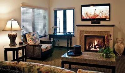 a living room with a fireplace with a tv above it at Pantai Inn in San Diego
