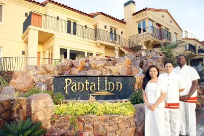 a family posing in front of a hotel sign at Pantai Inn in San Diego