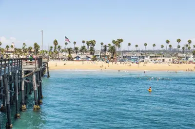 a beach with people in the water and a pier at 308 35th Street, Unit A (Lower) in Newport Beach
