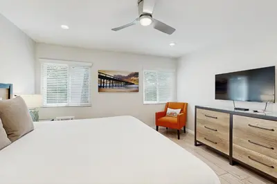 a white bedroom with a large bed and a flat screen tv at Villa Del Mar in San Clemente