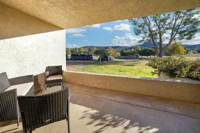 a balcony with a table and chairs and a view of a park at San Vicente Golf Resort in Ramona