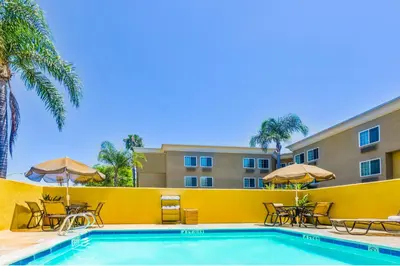 a pool with chairs and umbrellas in front of a hotel at GreenTree Inn San Diego Mission Bay in San Diego