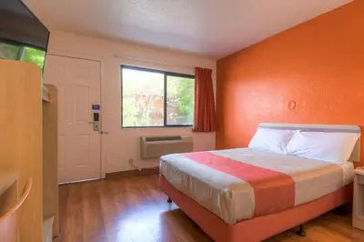 a bedroom with a bed with an orange wall at Motel 6-San Ysidro, CA - San Diego - Border in San Ysidro, San Diego