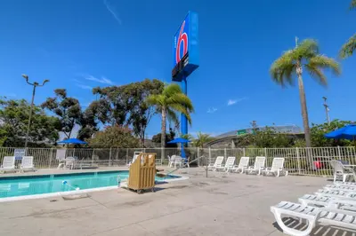 a pool with white chairs and a sign with a no sign at Motel 6-San Ysidro, CA - San Diego - Border in San Ysidro, San Diego