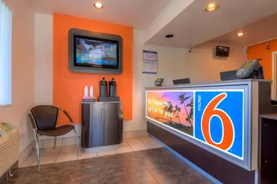 a large television in a room with an orange wall at Motel 6-San Ysidro, CA - San Diego - Border in San Ysidro, San Diego