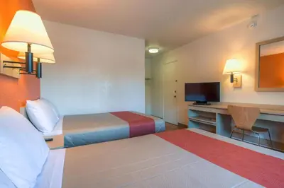 a hotel room with two beds and a desk with a television at Motel 6-San Ysidro, CA - San Diego - Border in San Ysidro, San Diego