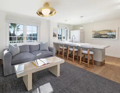 a living room with a couch and a kitchen at Bay Shores Peninsula Hotel in Newport Beach