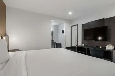 a bedroom with a large white bed and a flat screen tv at Motel 6-Escondido, CA in Escondido