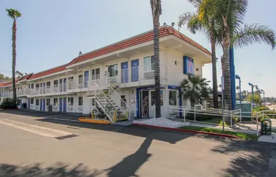 a building with palm trees in front of a street at Motel 6-La Mesa, CA - San Diego in La Mesa