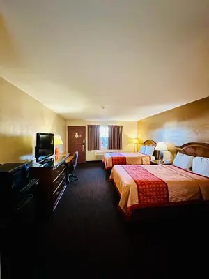 a hotel room with two beds and a television at Franciscan Inn Motel in Vista