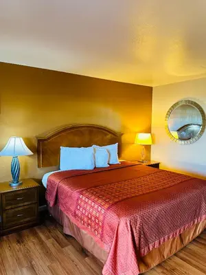 a hotel room with a bed with a red bedspread at Franciscan Inn Motel in Vista