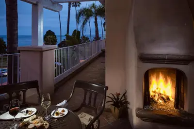 a dining table with a fireplace on a balcony at La Valencia Hotel in San Diego