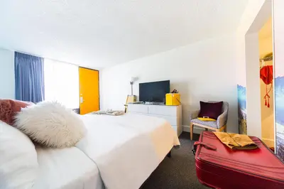 a hotel room with a bed and a red suitcase at Rambler Hotel in Chula Vista