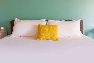 a bed with white pillows and a yellow pillow at Rambler Hotel in Chula Vista