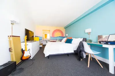 a bedroom with a bed with a guitar and a desk at Rambler Hotel in Chula Vista