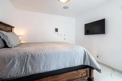 a white bedroom with a bed and a flat screen tv at Fantastic Mission Beach condo steps to the Beach in San Diego