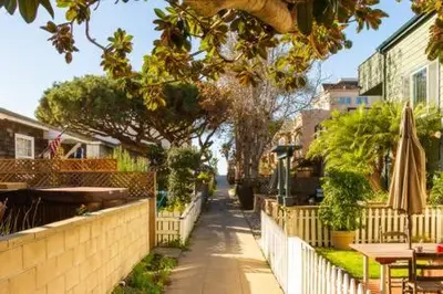 a sidewalk with a fence and a table and umbrella at Fantastic Mission Beach condo steps to the Beach in San Diego