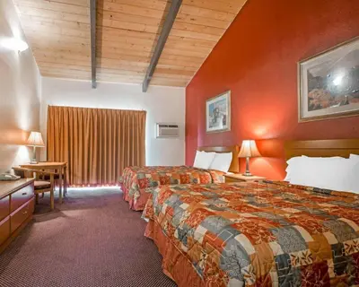 two beds in a hotel room with red walls at Rodeway Inn Fallbrook Downtown in Fallbrook
