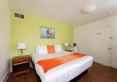 a bedroom with a large bed with an orange blanket at The Patriots Boutique Motel in San Clemente