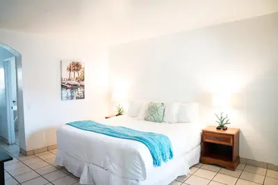 a bedroom with a white bed with a blue blanket on it at The Patriots Boutique Motel in San Clemente