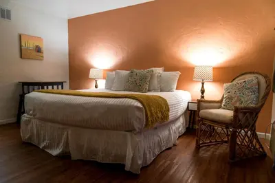 a hotel room with a large bed and a chair at The Patriots Boutique Motel in San Clemente