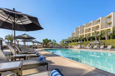 a swimming pool with lounge chairs and an umbrella at Hilton La Jolla Torrey Pines in San Diego