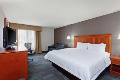 a hotel room with a bed and a flat screen tv at Hampton Inn San Marcos in San Marcos