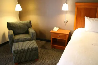 a hotel room with a bed and a chair and a phone at Hampton Inn San Marcos in San Marcos