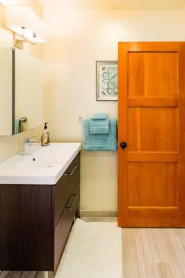 a bathroom with a sink and a wooden door at The Little Pumpkin Guest House in San Diego