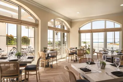 a restaurant with tables and chairs and windows at Hilton Garden Inn Carlsbad Beach in Carlsbad