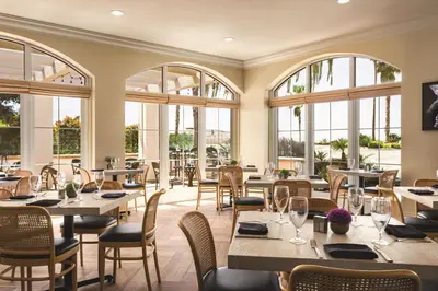 a restaurant with tables and chairs and windows at Hilton Garden Inn Carlsbad Beach in Carlsbad